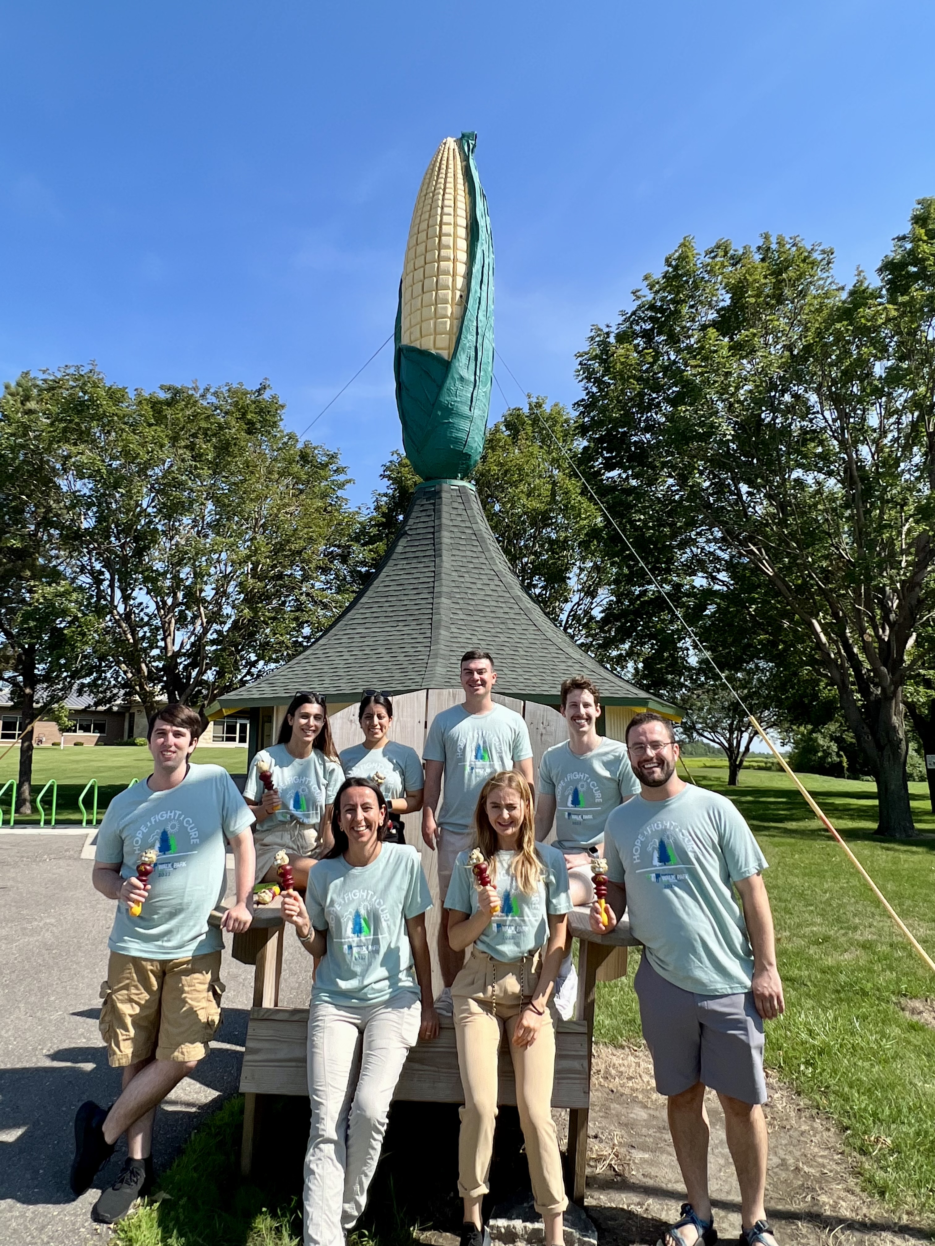 Dr. Balbo's team at a Renville Co. community event, standing in front of a corn cob monument.